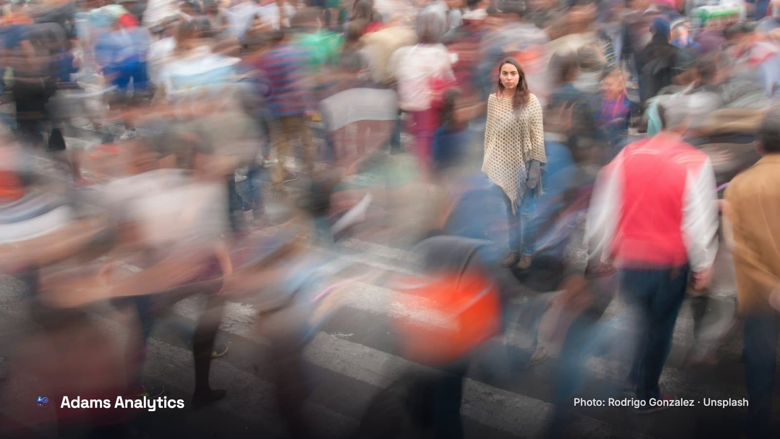 A blurred crowd of people crossing a busy city street