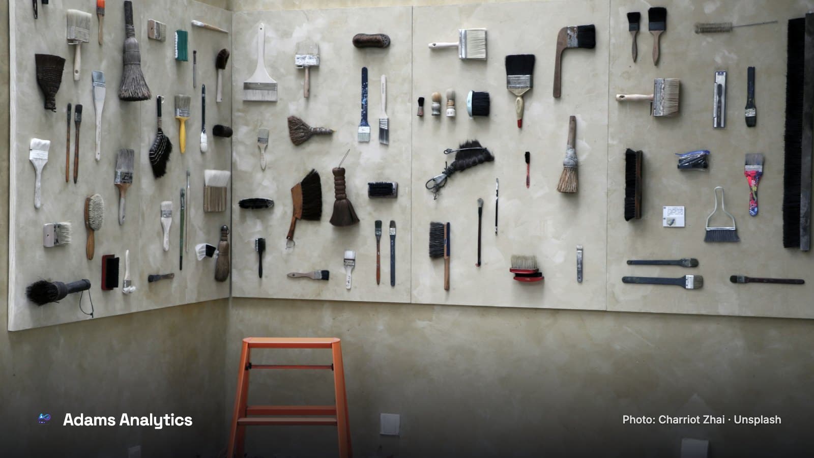 Hand tools hung in neat rows on a workshop wall, with an orange stepladder below