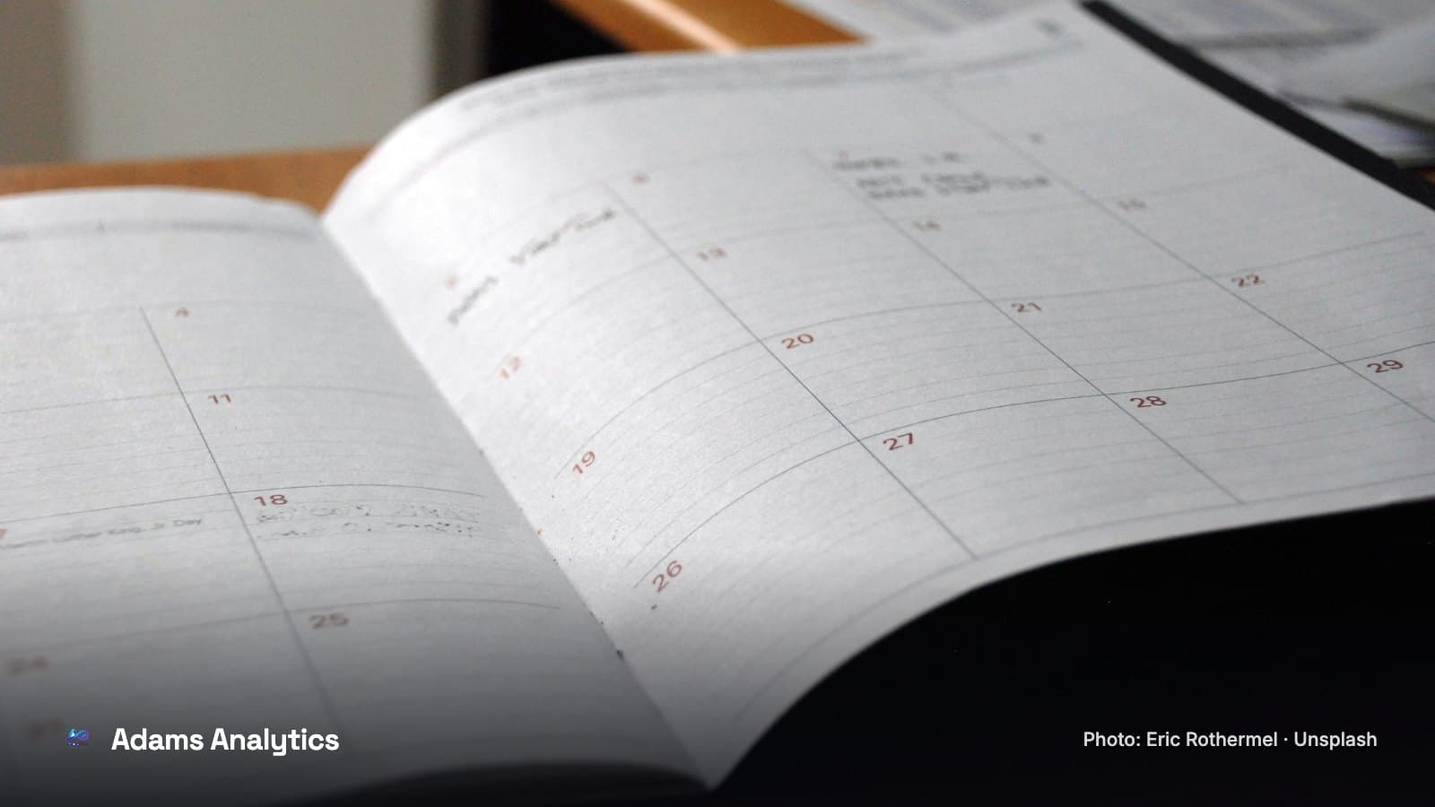 A monthly planner lying open on a wooden desk