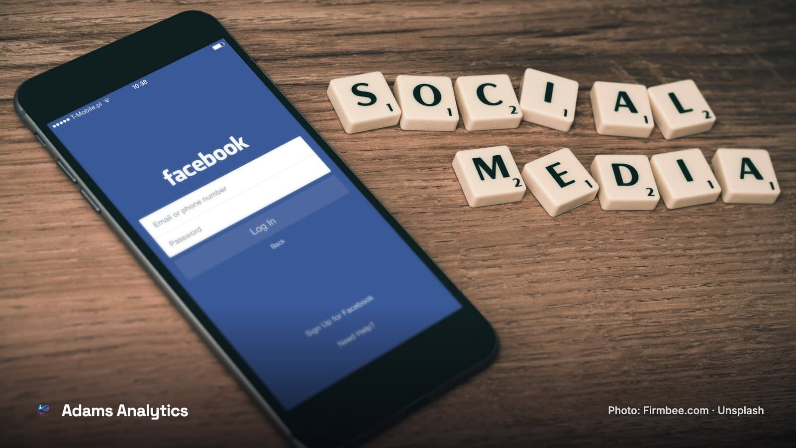 A phone showing the Facebook sign-in screen next to wooden letter tiles spelling social media