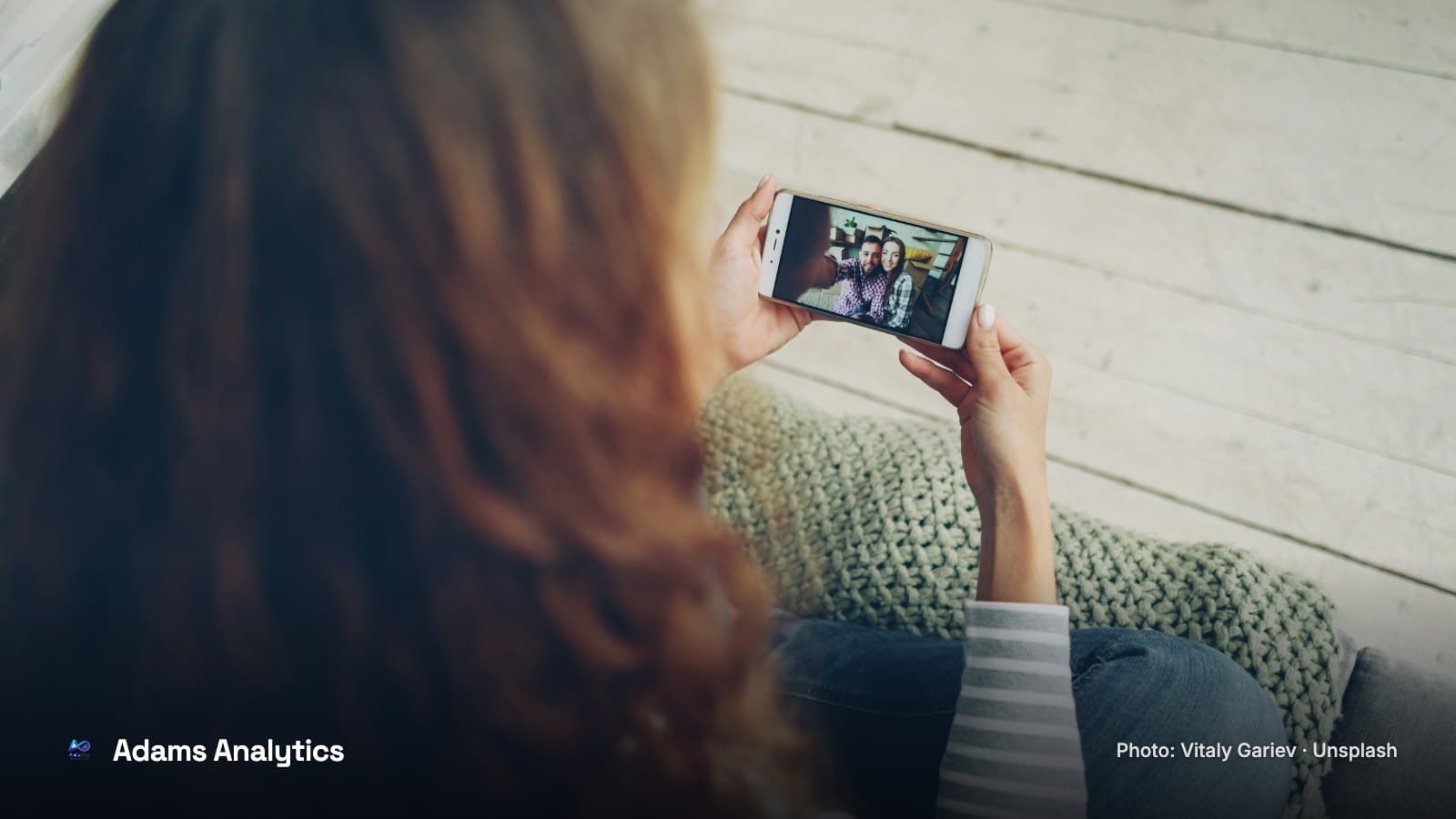 A woman relaxing on a sofa while watching a video on her phone