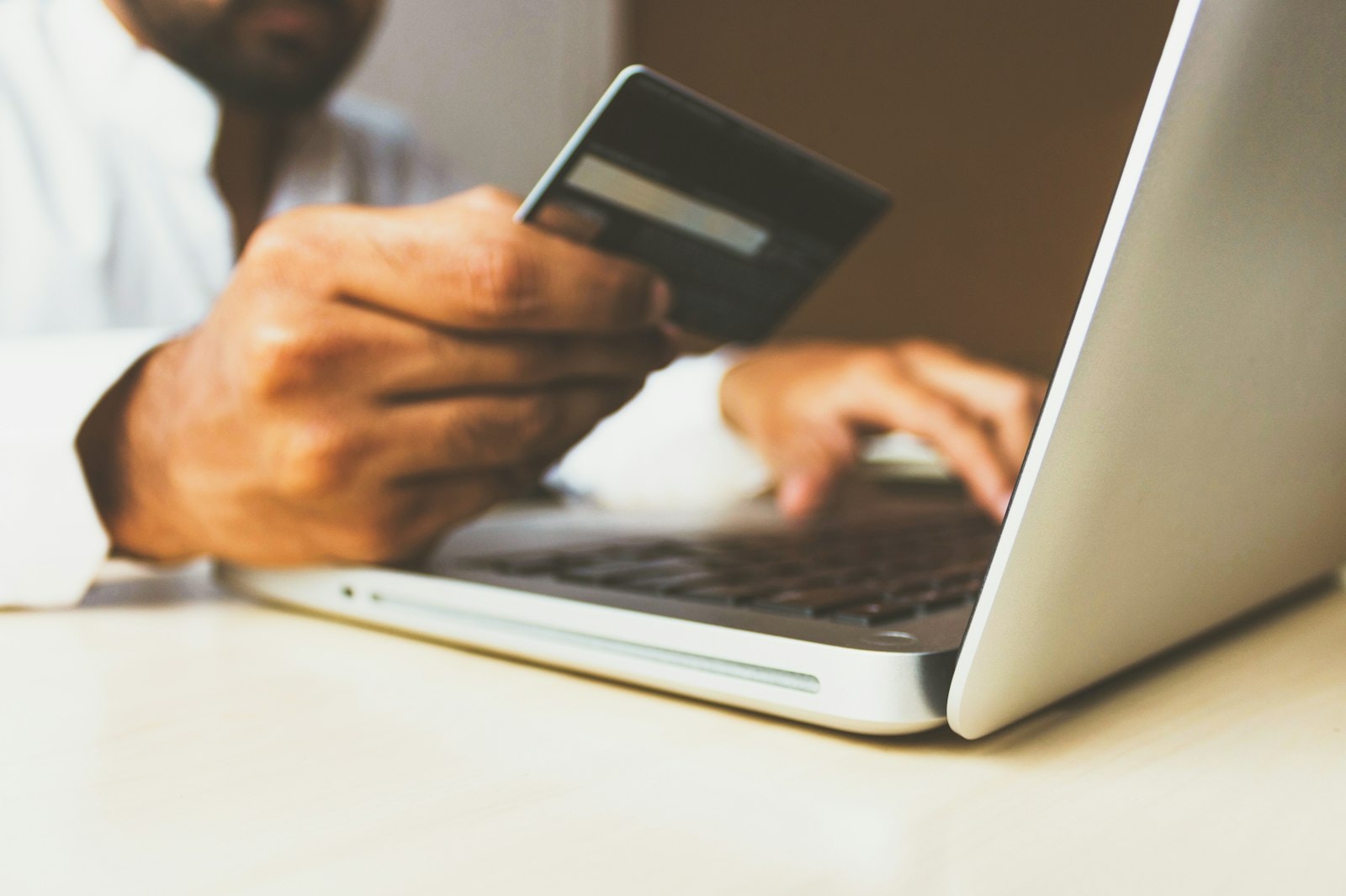 A person paying online with a bank card and a laptop