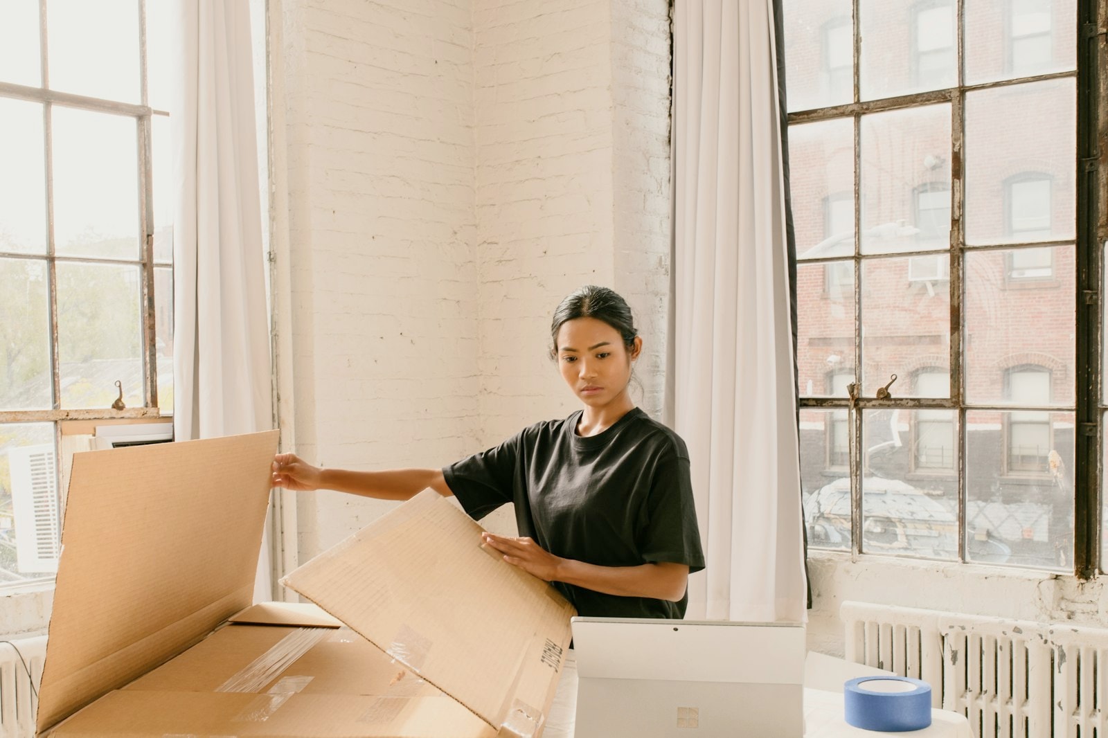 A young woman preparing cardboard boxes for orders at home
