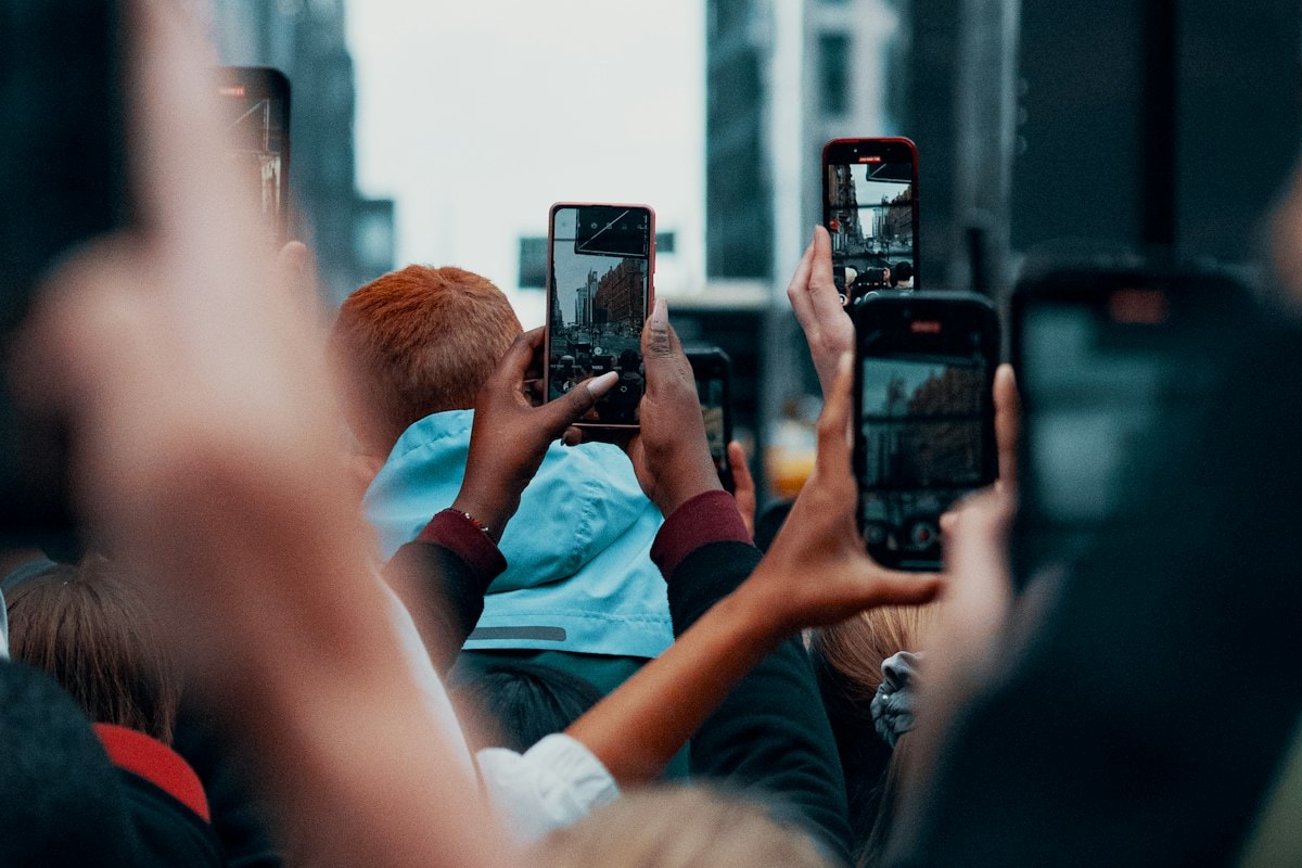 A crowd holding up smartphones to record a street event