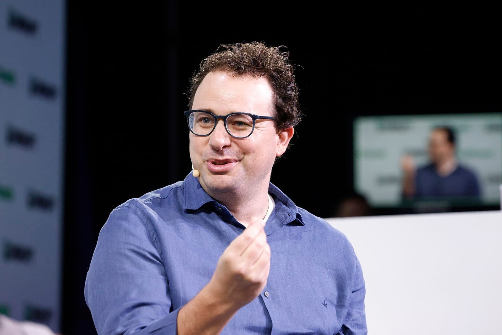 Dario Amodei, smiling, in a blue shirt on a conference stage