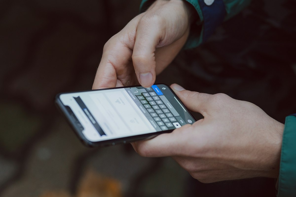 A hand holding a smartphone and typing a message