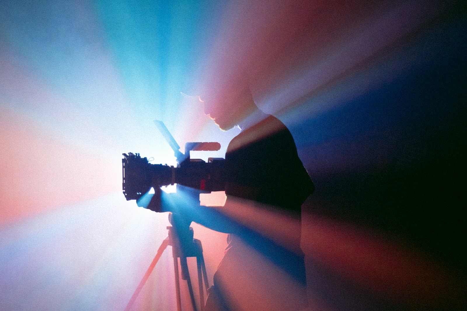 A video camera on a tripod lit by colored studio lights