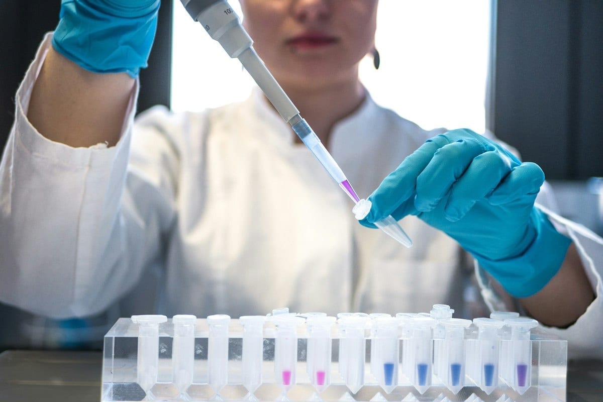 A scientist using a pipette with a row of test tubes
