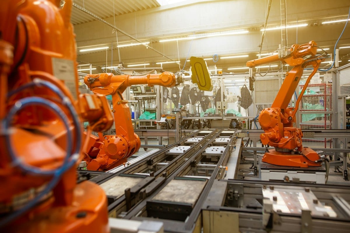 Orange robotic arms working on a modern factory line