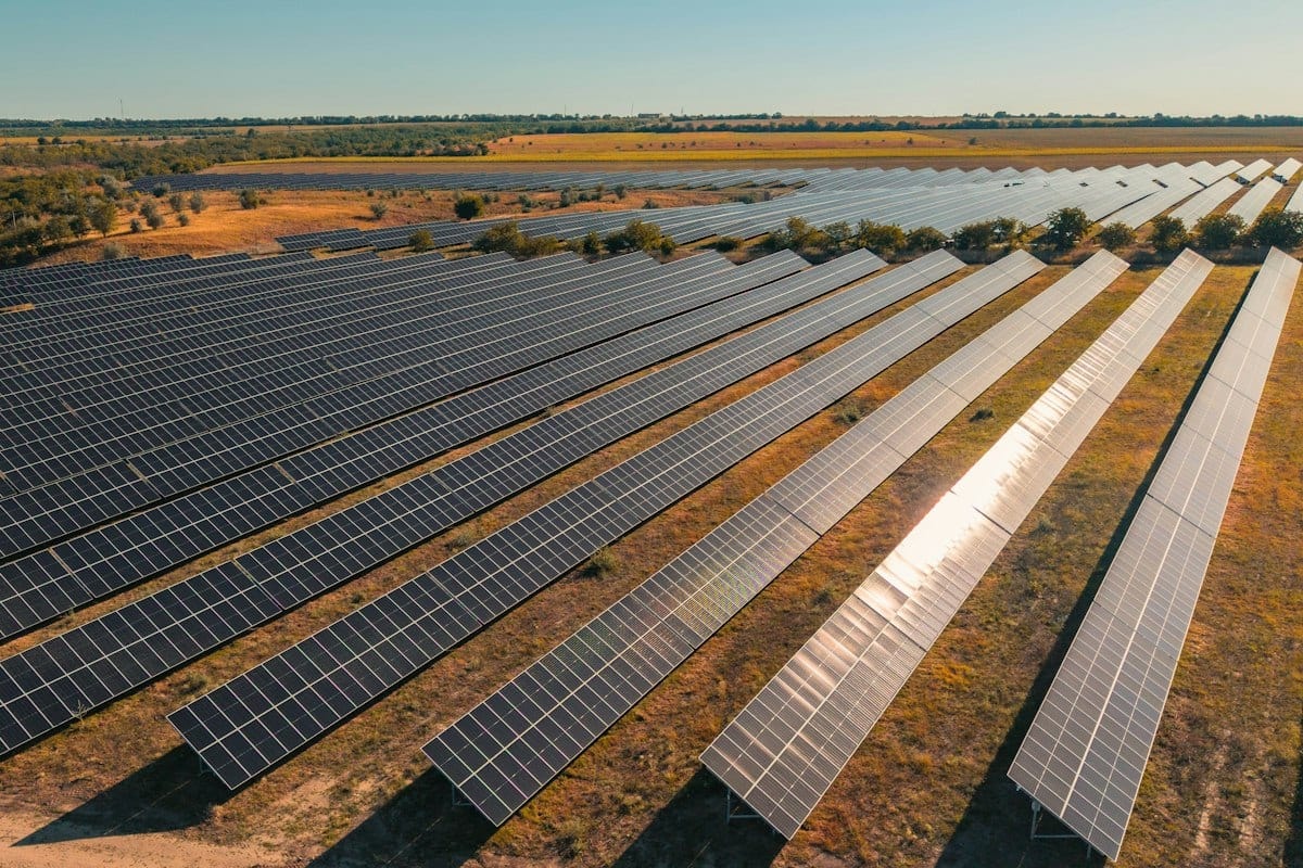 Rows of solar panels stretching across a large field under a clear sky