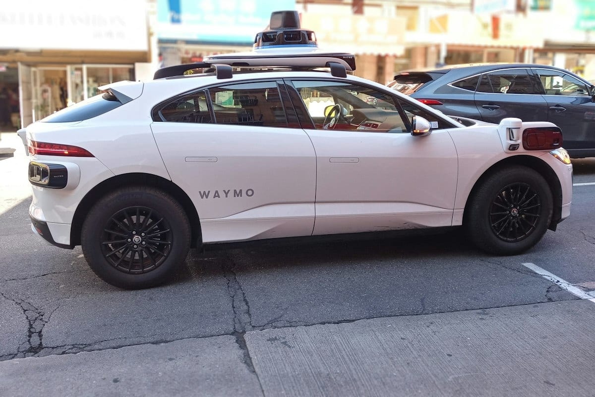 A white Waymo self-driving car on a city street